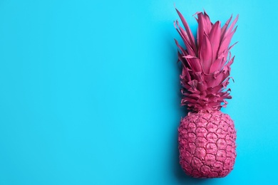 Photo of Pink pineapple on light blue background, top view with space for text. Creative concept