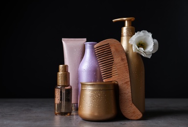 Photo of Different hair products, flower and wooden comb on grey table