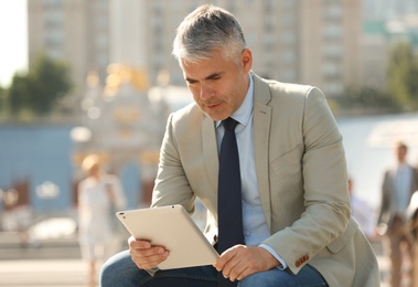Photo of Portrait of handsome businessman with tablet in city