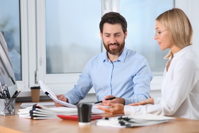 Happy businesspeople working with documents at table in office