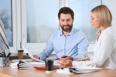 Photo of Happy businesspeople working with documents at table in office