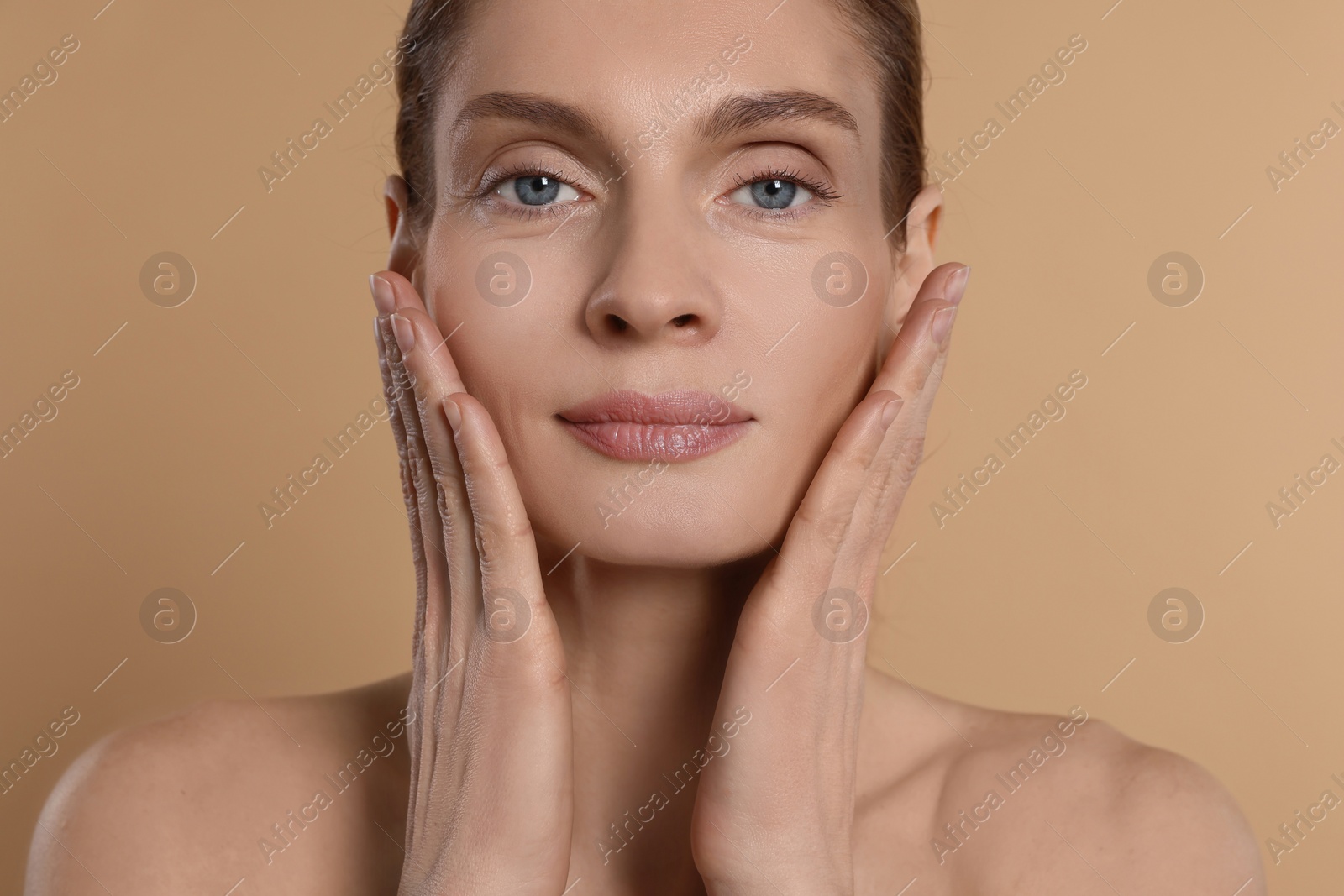 Photo of Woman massaging her face on beige background