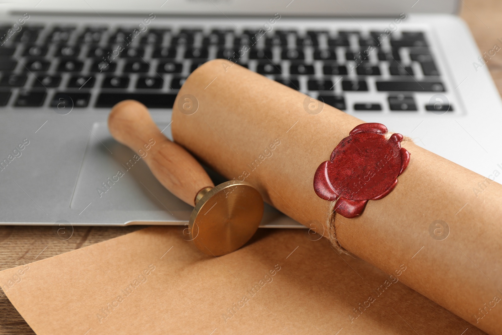 Photo of Notary's public pen and sealed document near laptop on wooden table, closeup