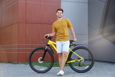 Photo of Handsome young man with bicycle on city street