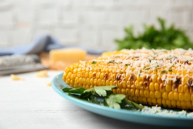 Photo of Plate of grilled corn cobs with grated cheese on white wooden table, closeup. Space for text