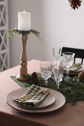 Photo of Christmas place setting with burning candle and other festive decor on table, closeup