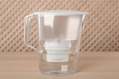 Photo of Filter jug with purified water on wooden table indoors