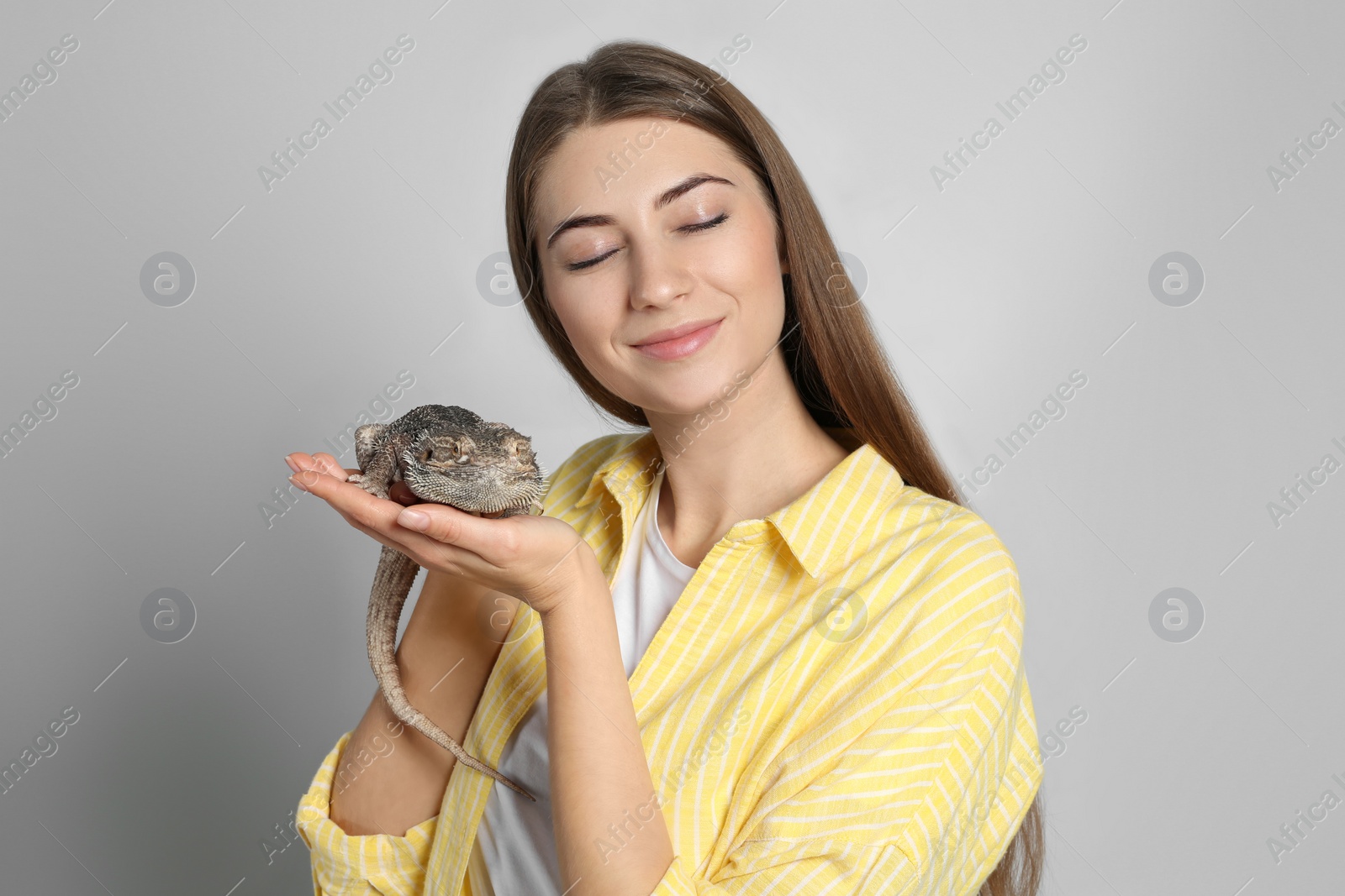 Photo of Woman holding bearded lizard on grey background. Exotic pet