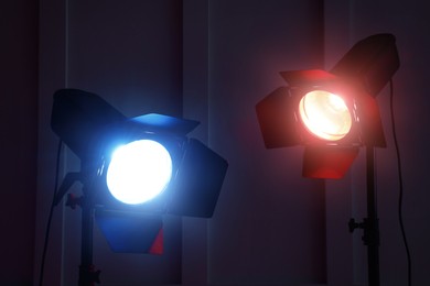 Bright red and blue spotlights near wall in dark room