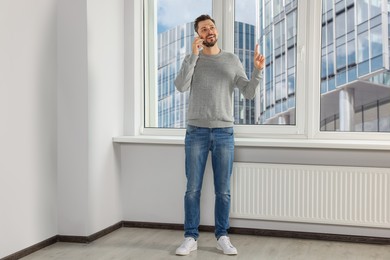 Photo of Man talking on phone near window indoors