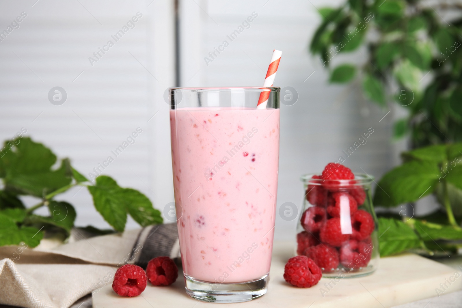 Photo of Glass of tasty raspberry smoothie on light table