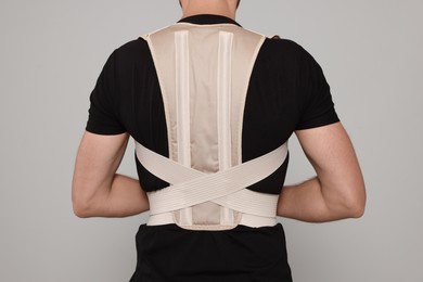 Closeup of man with orthopedic corset on grey background, back view