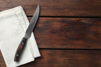 Photo of One sharp knife and napkin on wooden table, top view. Space for text