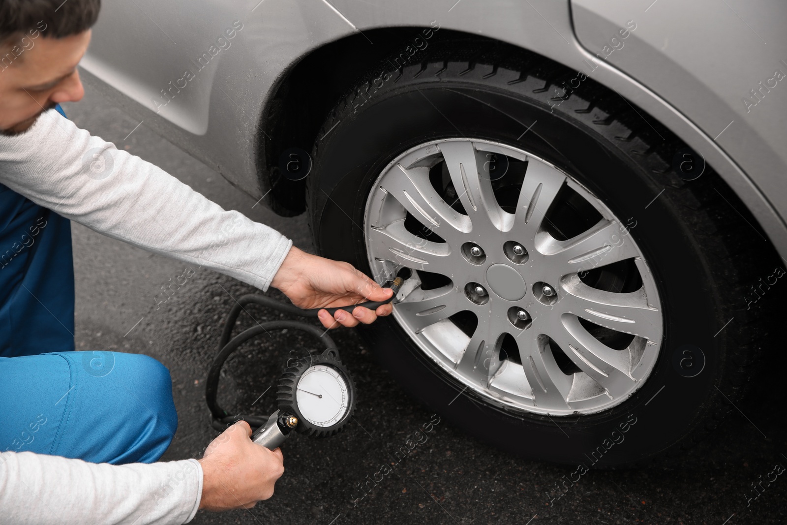 Photo of Mechanic checking tire pressure in car wheel at service station, closeup