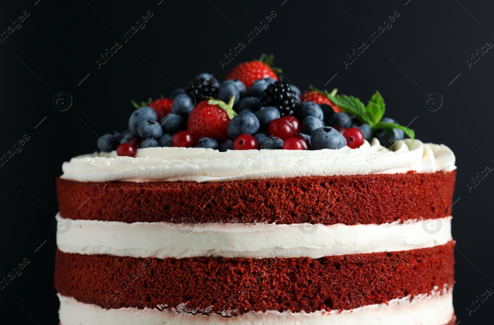 Photo of Delicious homemade red velvet cake with fresh berries on black background, closeup