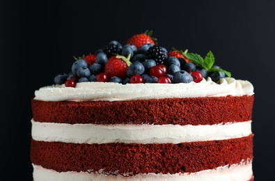 Photo of Delicious homemade red velvet cake with fresh berries on black background, closeup