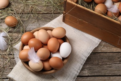 Fresh chicken eggs and dried hay on wooden table, above view