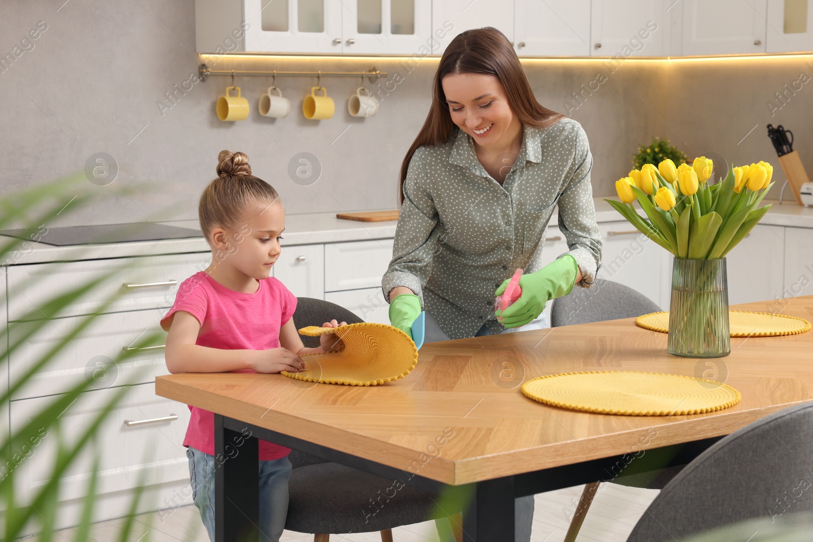 Photo of Spring cleaning. Mother and daughter tidying up kitchen together