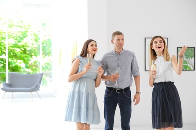 Group of people with glasses of champagne at exhibition in art gallery