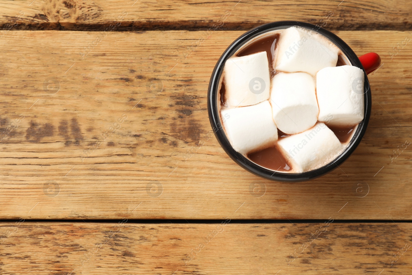 Photo of Tasty hot chocolate with marshmallows on wooden table, top view. Space for text