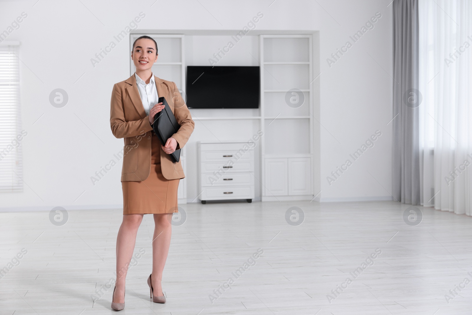 Photo of Happy real estate agent with leather portfolio in new apartment