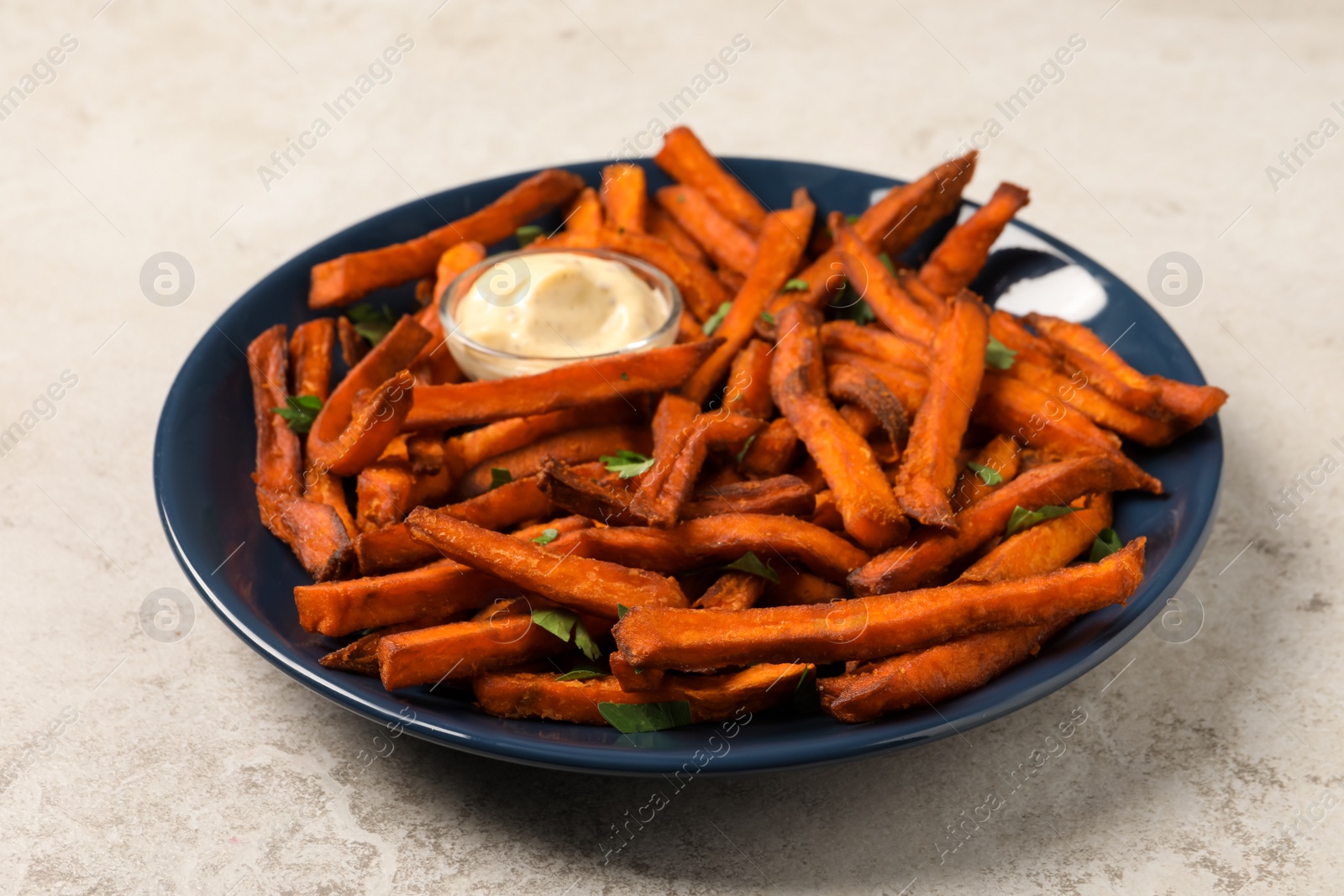 Photo of Delicious sweet potato fries served with sauce on light table