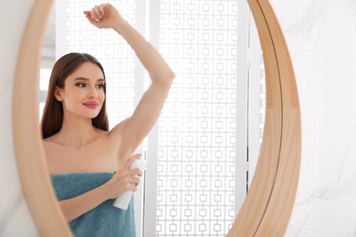 Photo of Beautiful young woman applying deodorant after shower in bathroom