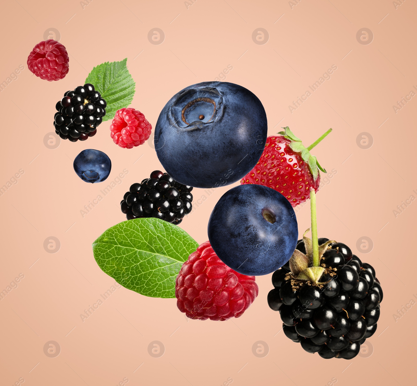 Image of Many different fresh berries falling on pink beige background