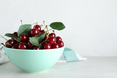 Photo of Sweet juicy cherries on light marble table. Space for text