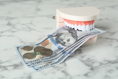Photo of Educational dental typodont model and money on white marble table. Expensive treatment