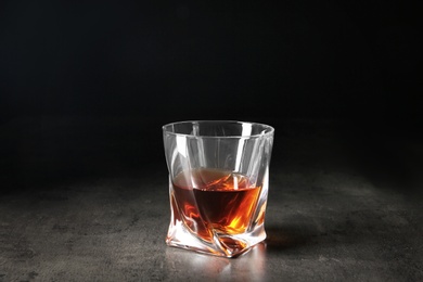 Photo of Glass of whiskey on table against dark background