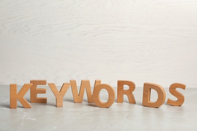 Photo of Word KEYWORDS made of wooden letters on light marble table