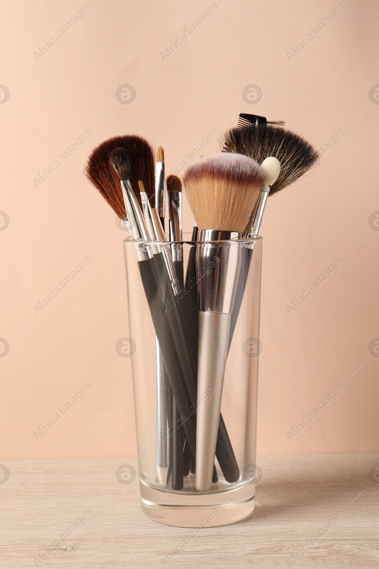 Photo of Set of professional makeup brushes on table against beige background