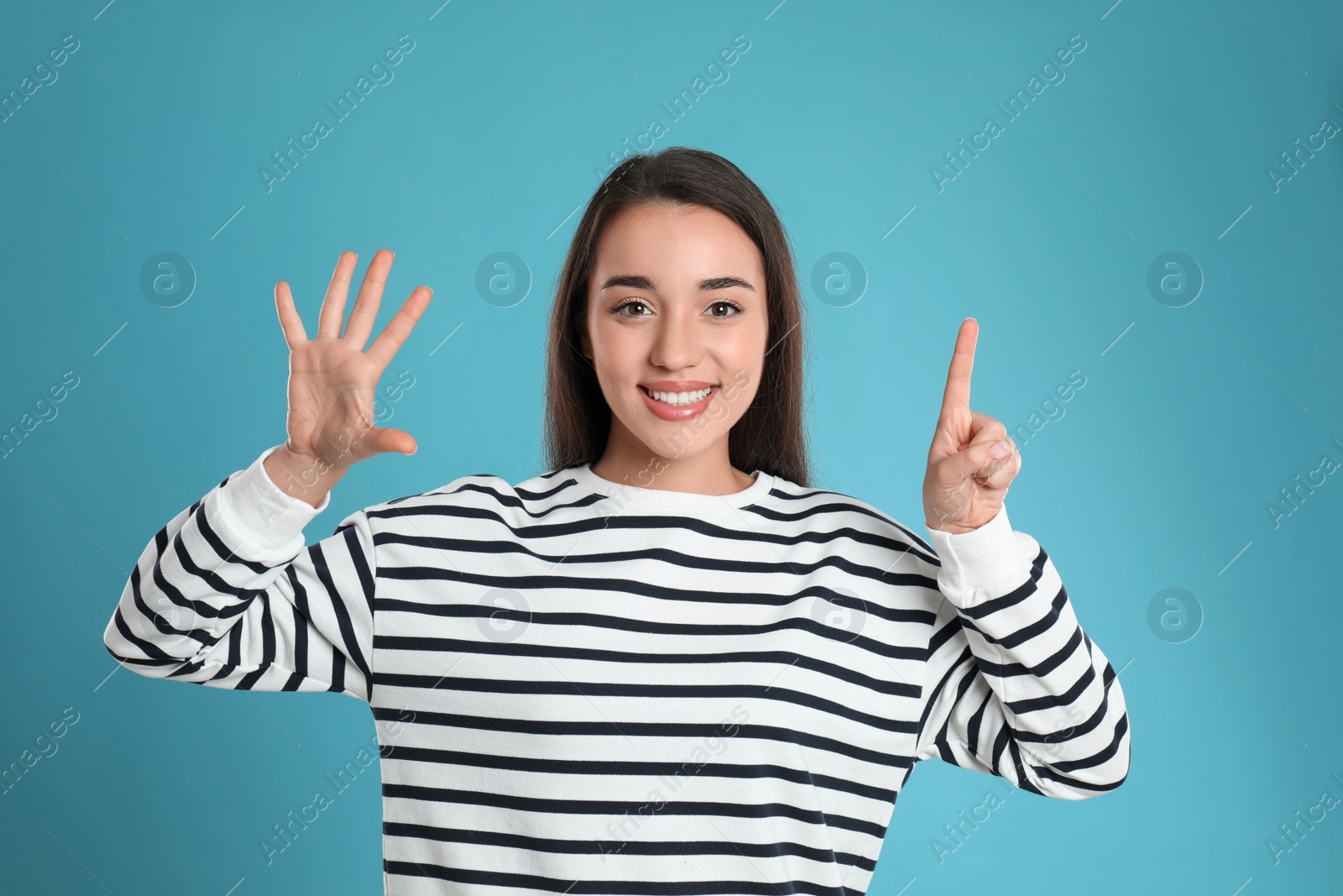 Photo of Woman showing number six with her hands on light blue background