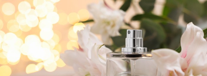 Bottle of perfume and beautiful lily flowers against beige background with blurred lights, closeup. Space for text