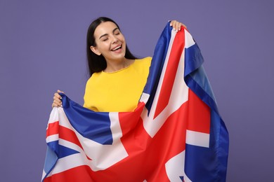 Photo of Happy young woman with flag of United Kingdom on violet background