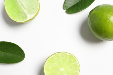 Photo of Fresh ripe limes and leaves on white background, flat lay