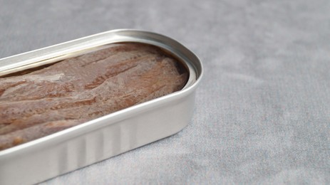 Canned anchovy fillets on light gray table, space for text