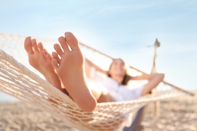 Photo of Young woman relaxing in hammock outdoors, focus on legs