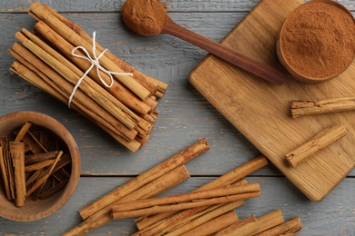 Photo of Aromatic cinnamon sticks and powder on grey wooden table, flat lay