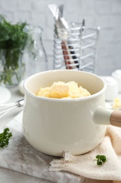 Saucepan with tasty mashed potato on gray table