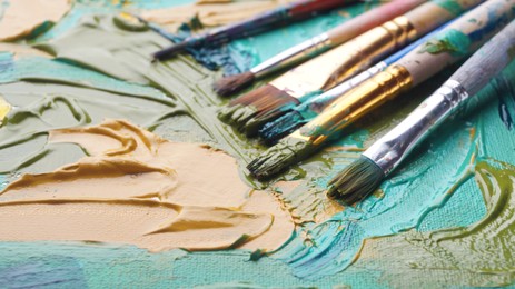 Photo of Many brushes on artist's palette with mixed paints, closeup