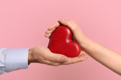 Photo of Man and woman with decorative heart on color background, closeup