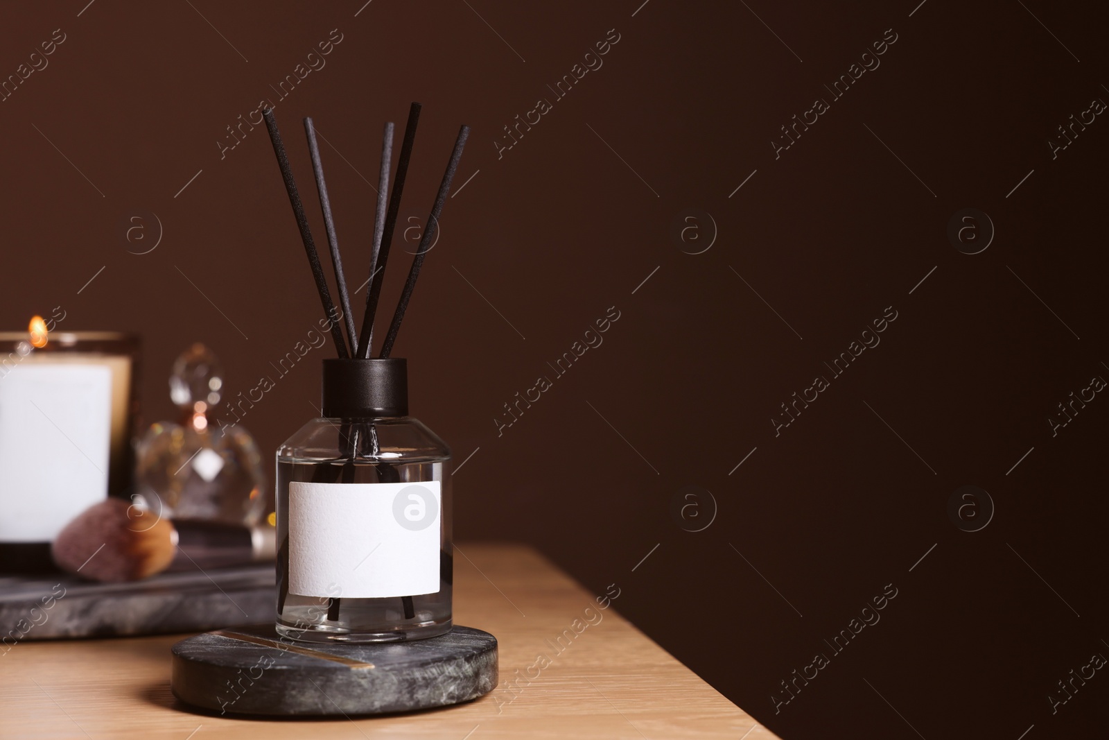 Photo of Aromatic reed air freshener on wooden table, space for text