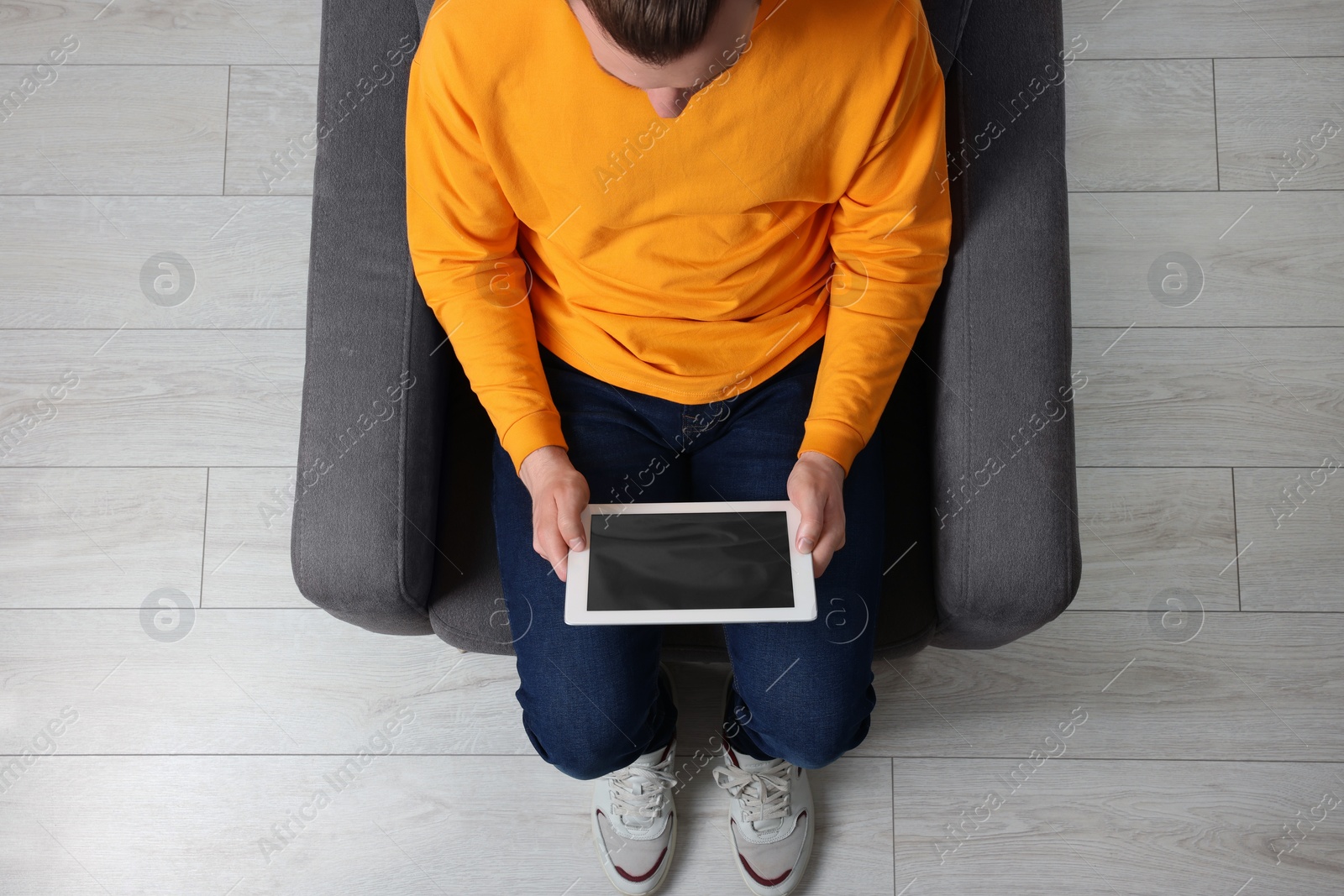 Photo of Man working with tablet in armchair, top view