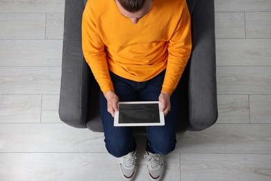 Photo of Man working with tablet in armchair, top view