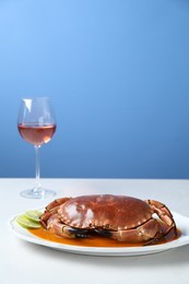 Delicious crab with sauce and lime on white table against light blue background. Space for text