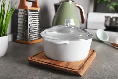 Pot with lid and other cooking utensils on grey countertop in kitchen