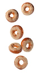 Image of Many fresh bagels with sesame seeds falling on white background