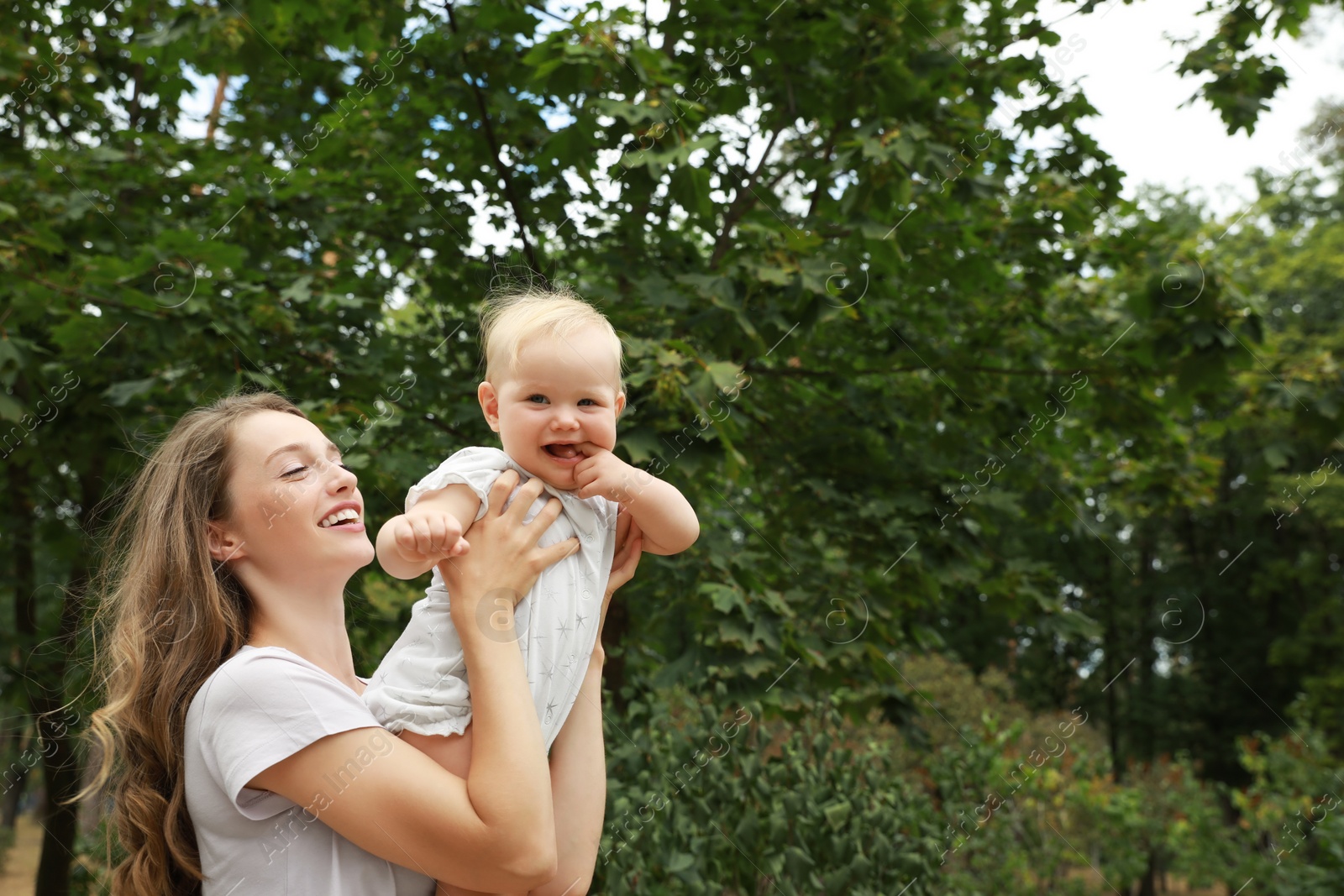 Photo of Mother with her cute baby spending time together outdoors. Space for text